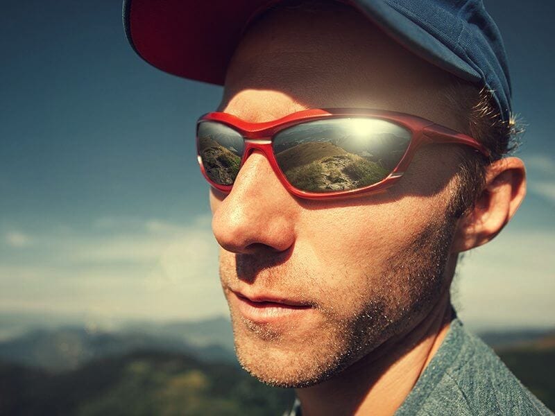 Man in sun glasses with mountain mirorred in it