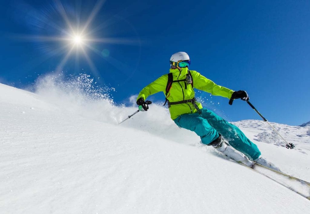 Skier skiing downhill during sunny day in high mountains