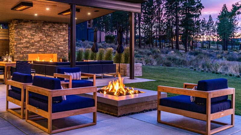 A peaceful backyard with a firepit as well as an outdoor fireplace