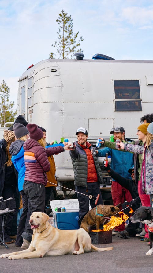 People and dogs tailgating around a custom camper in the snow