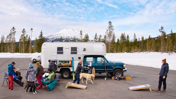 Winter tailgating in front of a custom camper with Mt. Bachelor behind