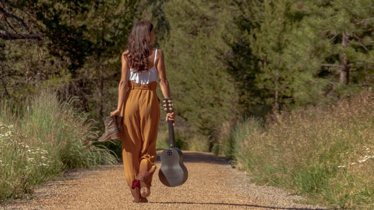 Image of a woman carrying boots and a Outdoor Ukelele