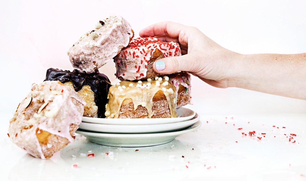 A hand reaching for a croissant donut from Too Sweet Cakes