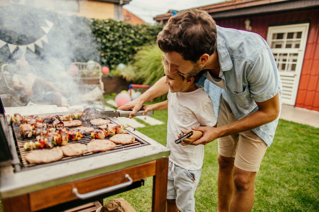 Dad grilling outside with his son