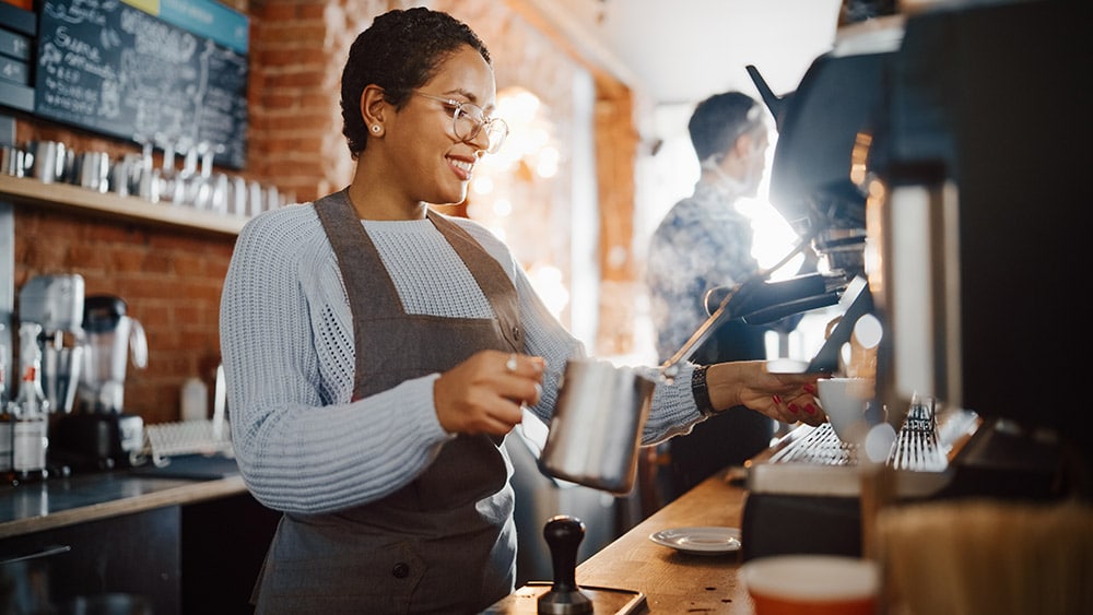 woman employee making coffee at coffee shop