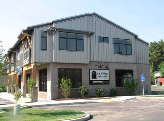 Grey building with green shrubs and grass around. Classic Coverings building