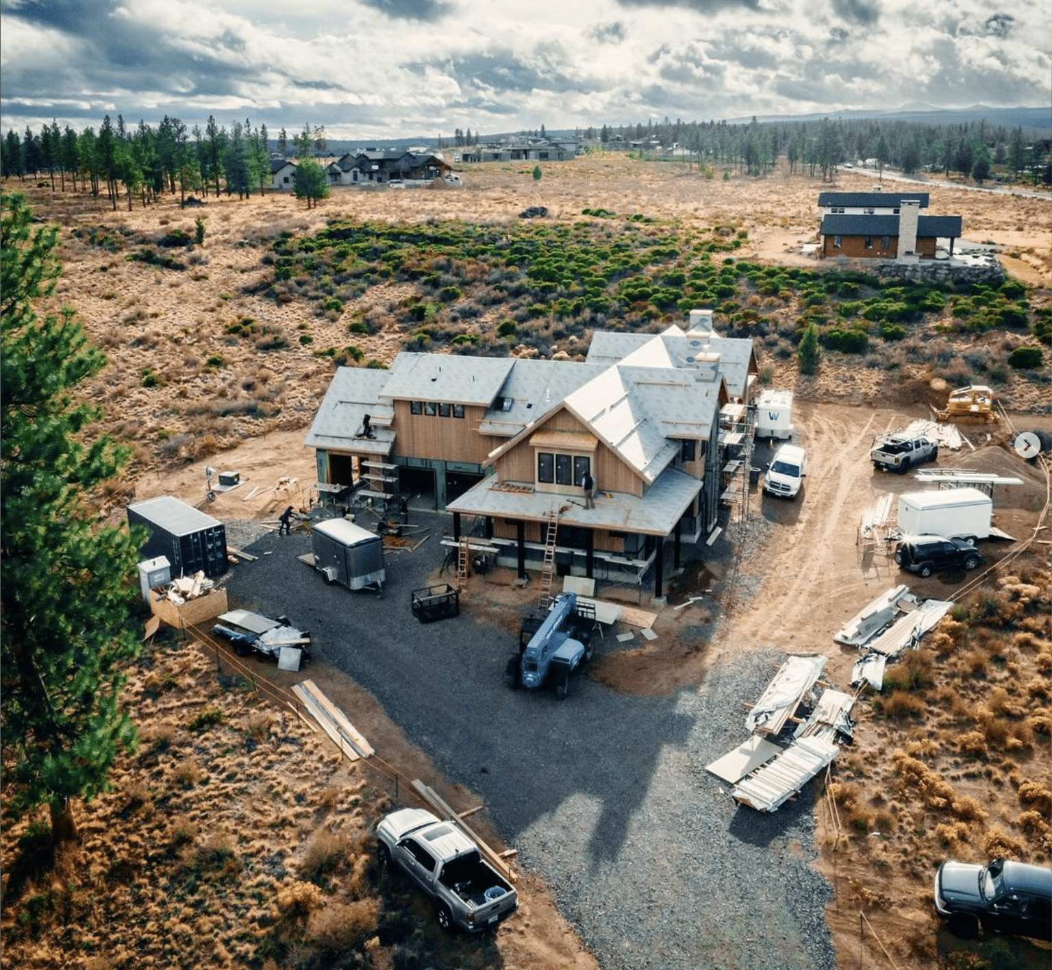 Job site of a large house under construction with trucks surrounding it.