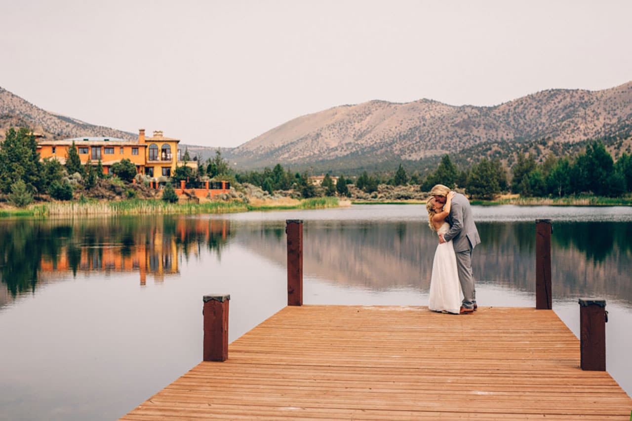 Bride and groom kissing by water