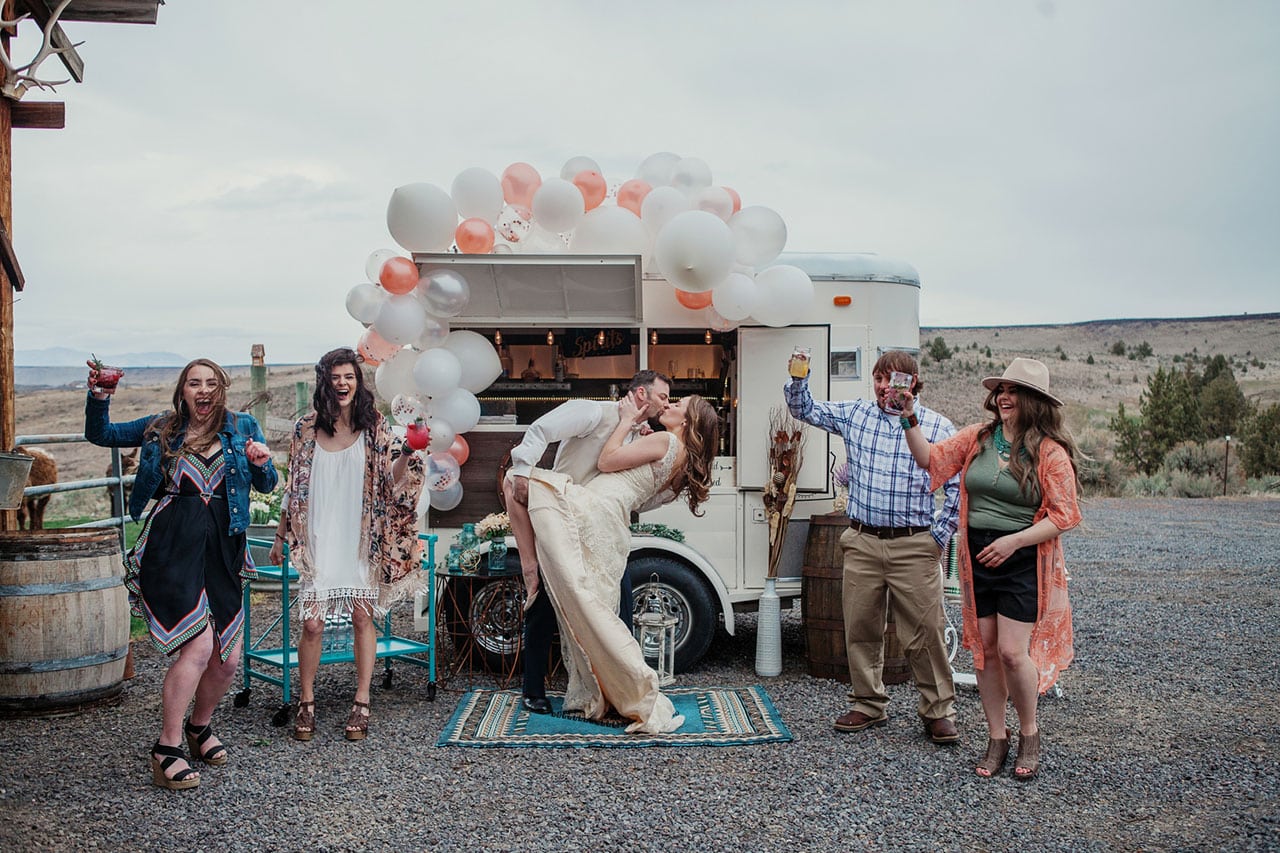 Bride and groom kissing in front of drink cart