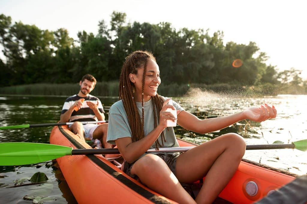 couple kayaking puts on sunscreen