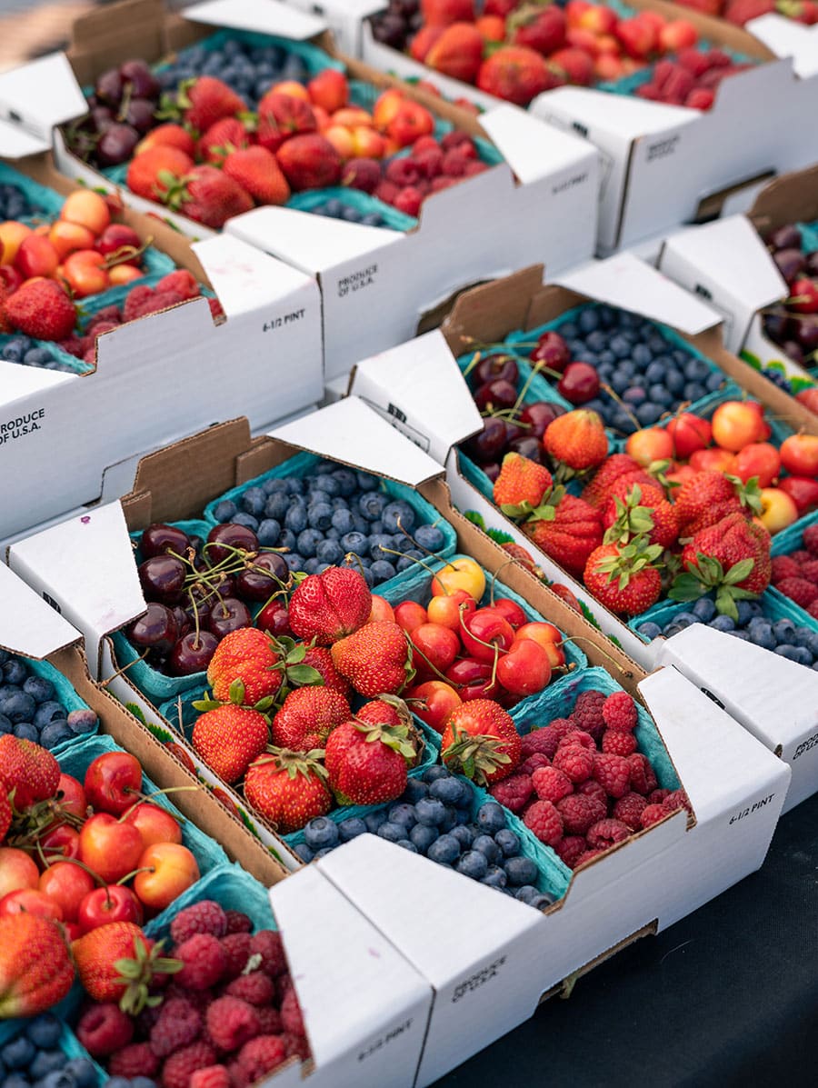 Strawberries, blueberries, cherries and raspberries in boxes at farmers market
