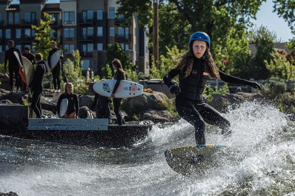 Woman riding the green wave with helmet on