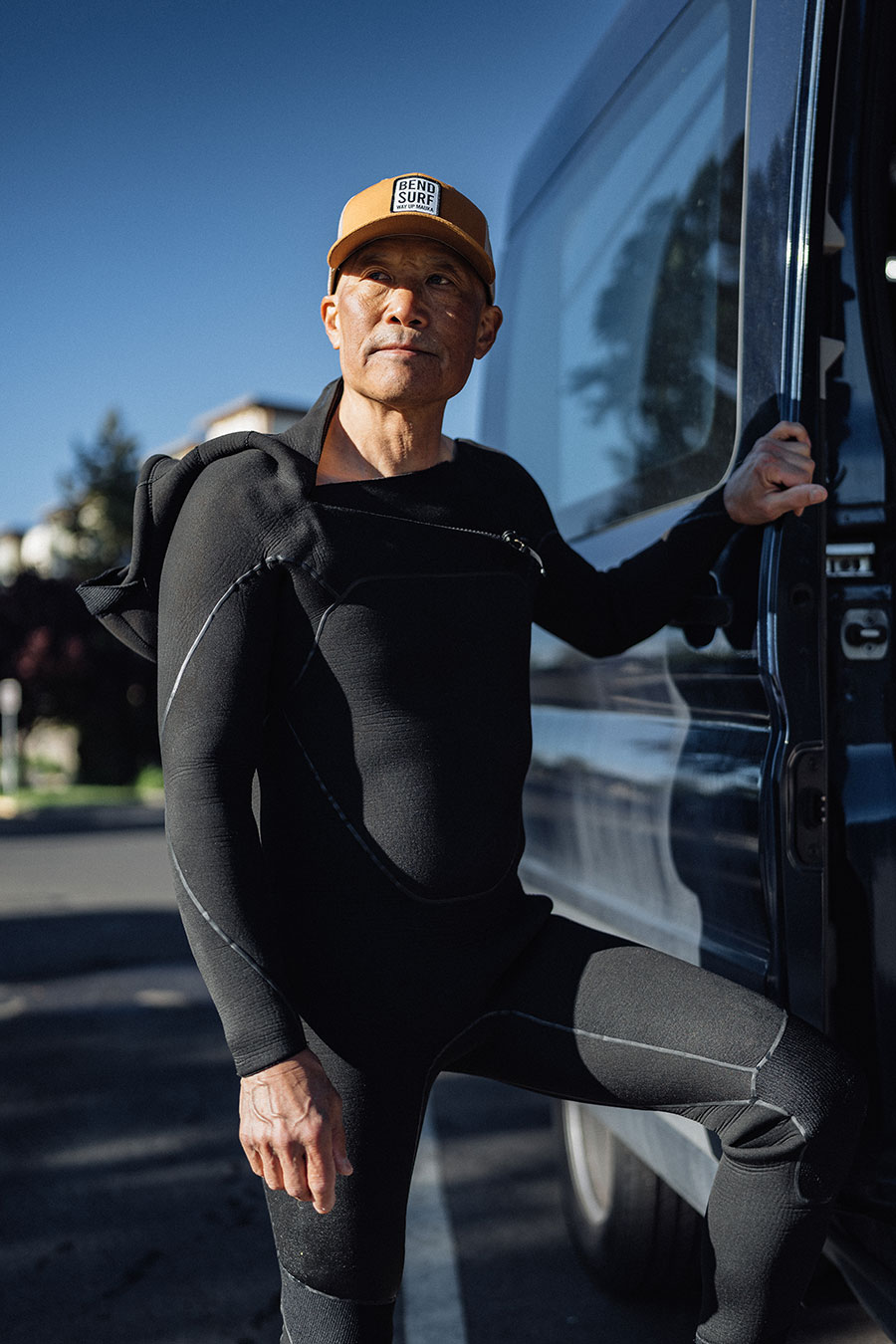 Surfer looking out by the Green Wave from van.