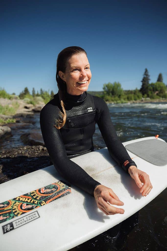Woman laughing with surfboard in the sun