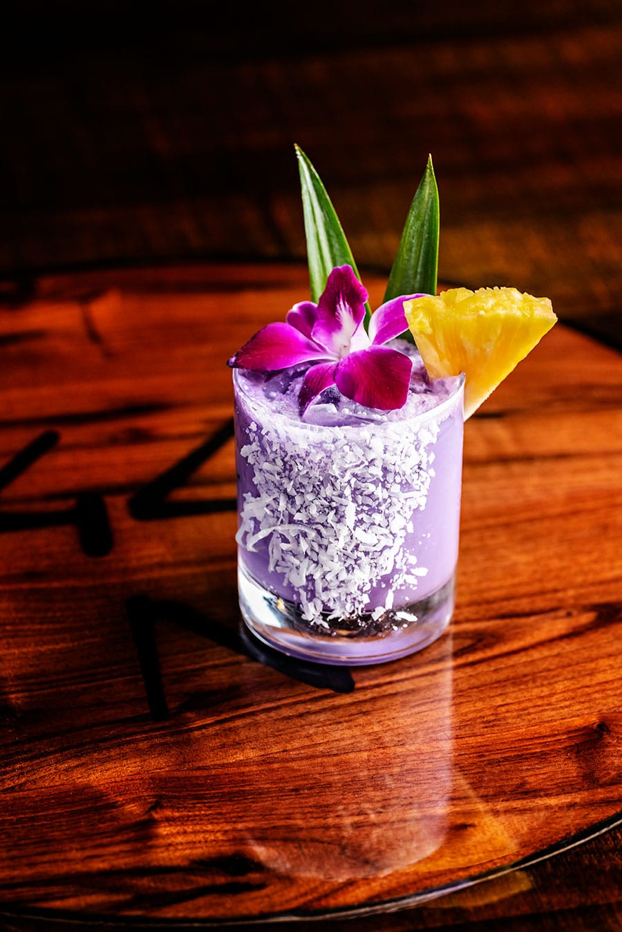 Purple cocktail with salted rim on table.