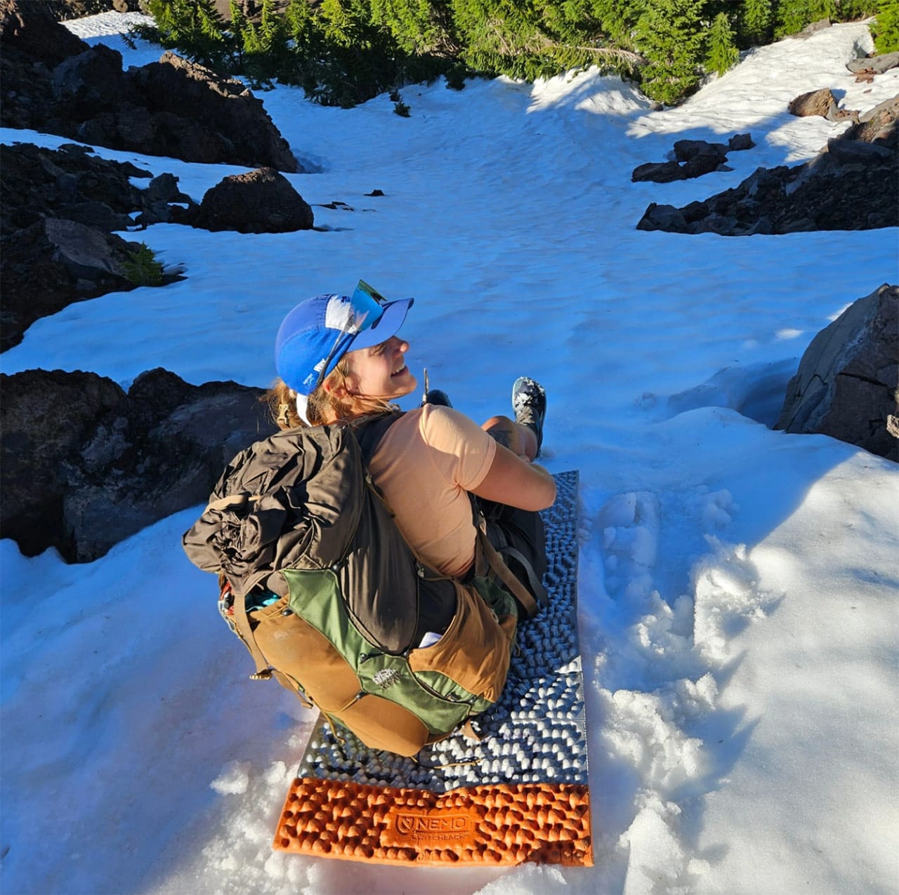 jess sledding down snow on foam sleeping pad on pct trail