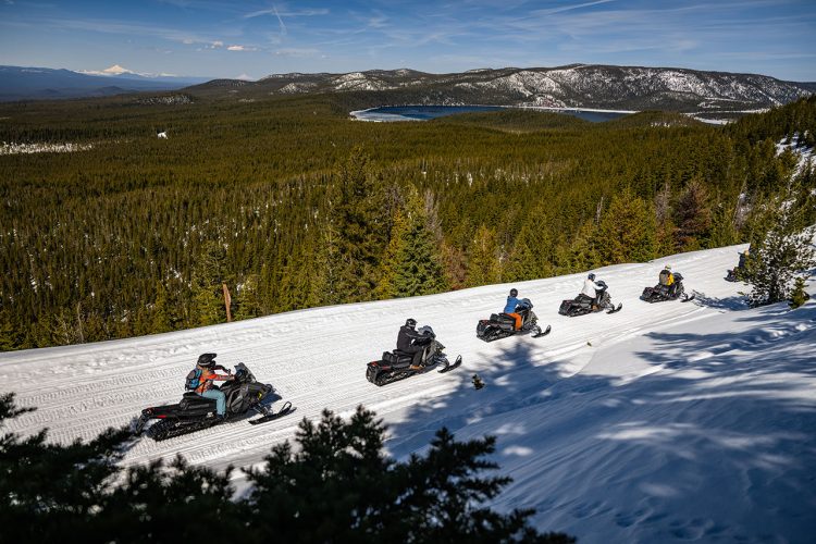 Snowmobilers driving through mountains