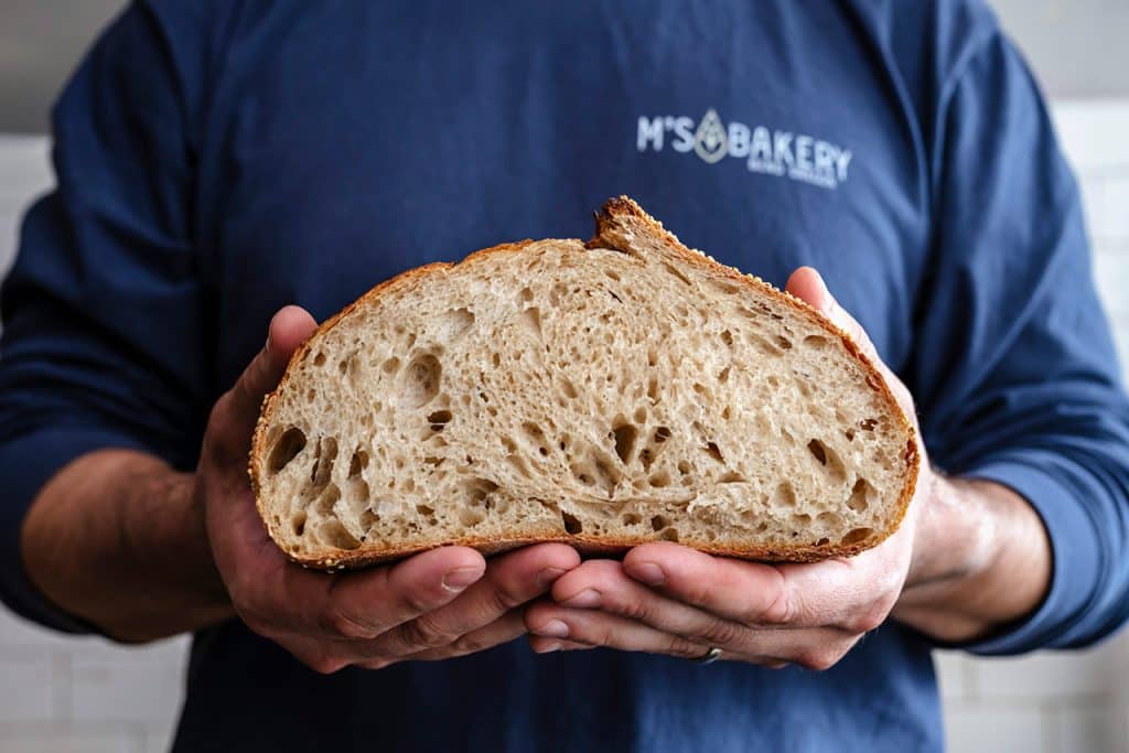 M's Bakery Holding Fresh Loaf of Bread Old Mill Bend