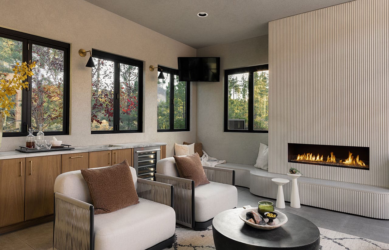 Outdoor patio remodel with tv on wall, windows, bar, chairs and inset fireplace