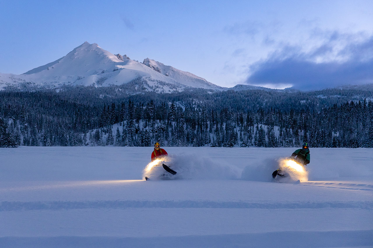 snowmobiling in snowy open space to backcountry ski