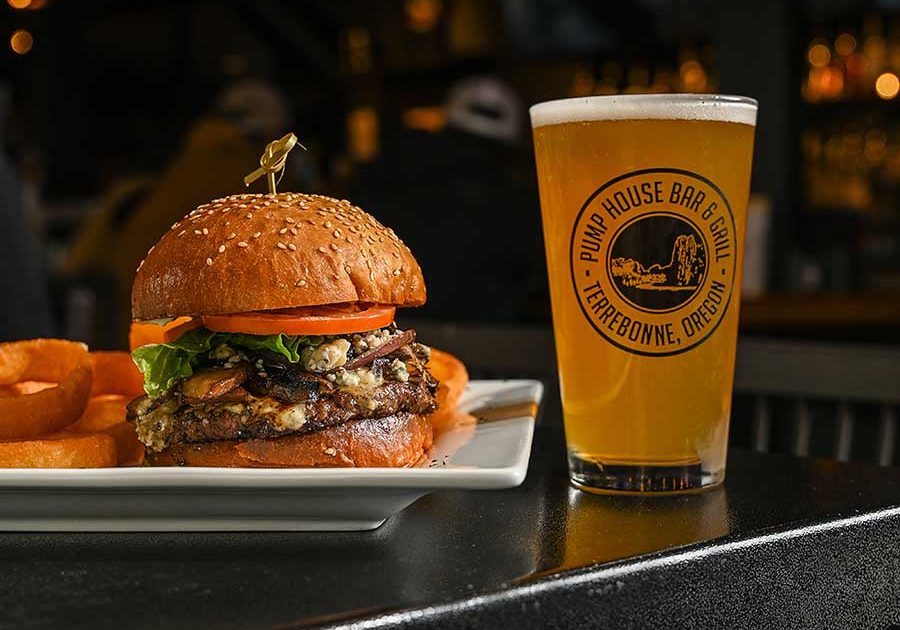 Burger on plate with beer on table at Pump House Bar and Grill