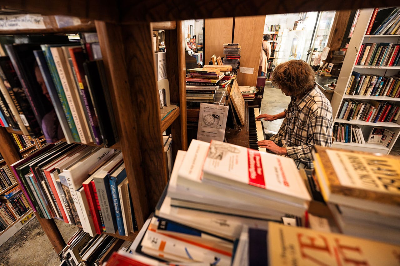 Person sitting at piano in bookshop playing music