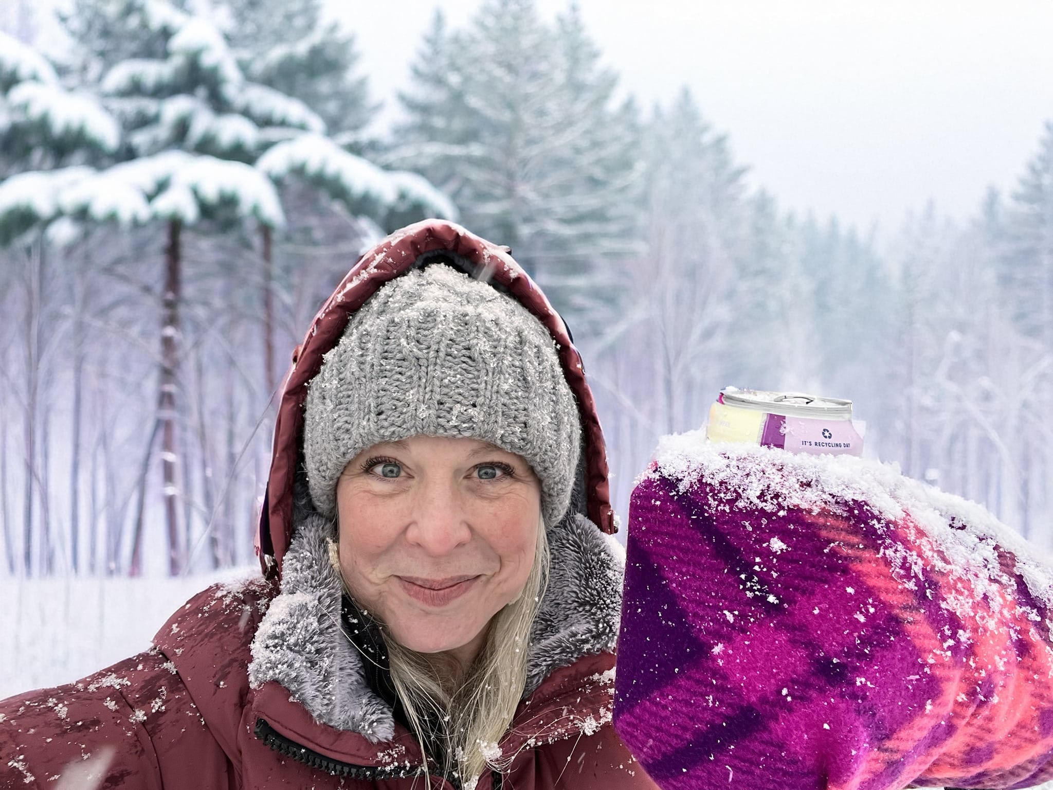 Sherrise Erlandson holding up her Giddyup glove holding a canned beverage in the snow outside.