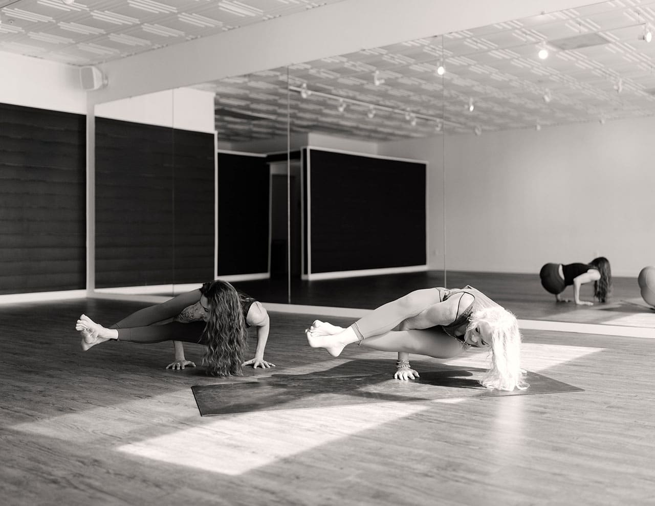 two people do yoga on mats in studio