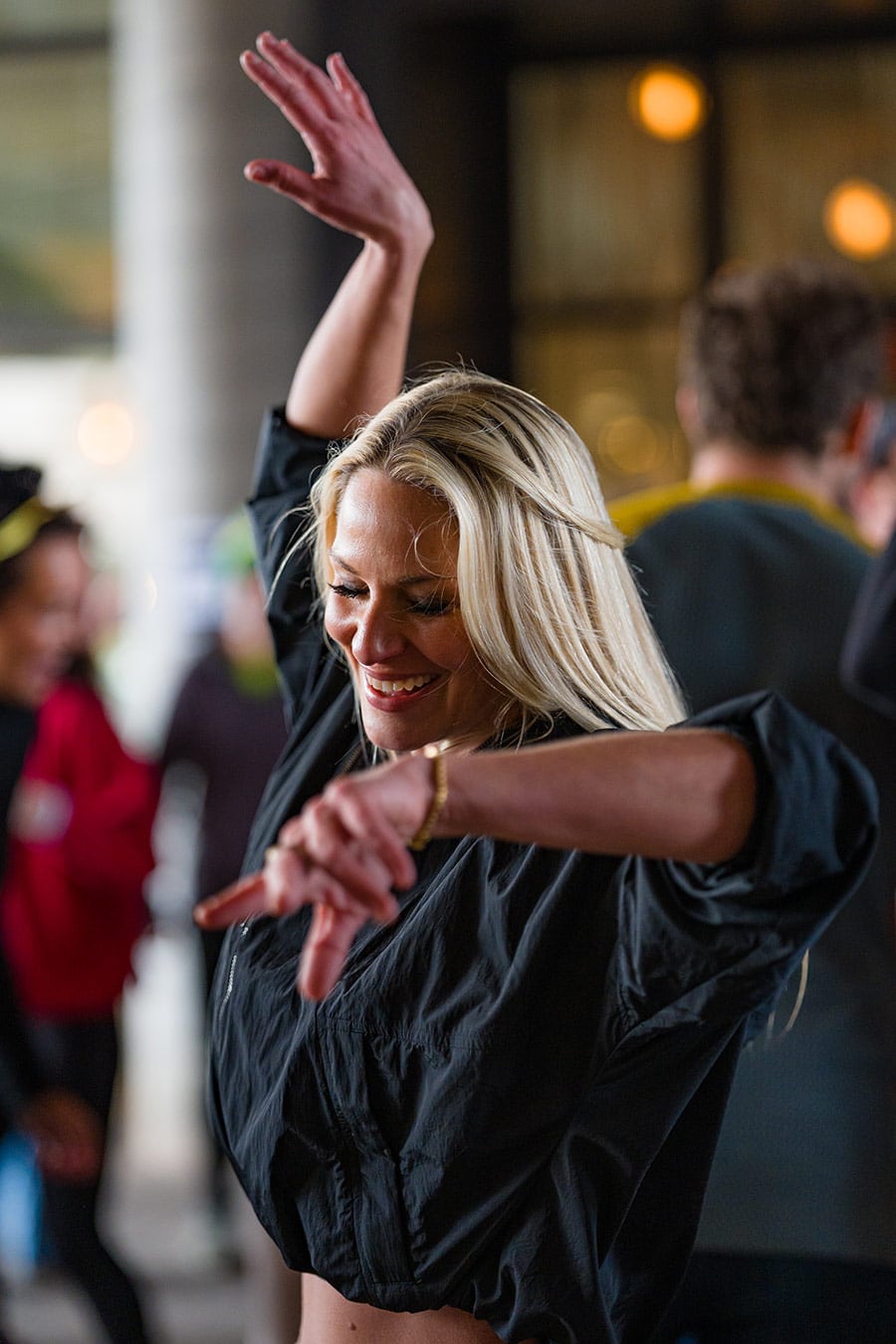Woman with hands in air dancing at a Get Up and Groove Dance Party at a coffee shop.