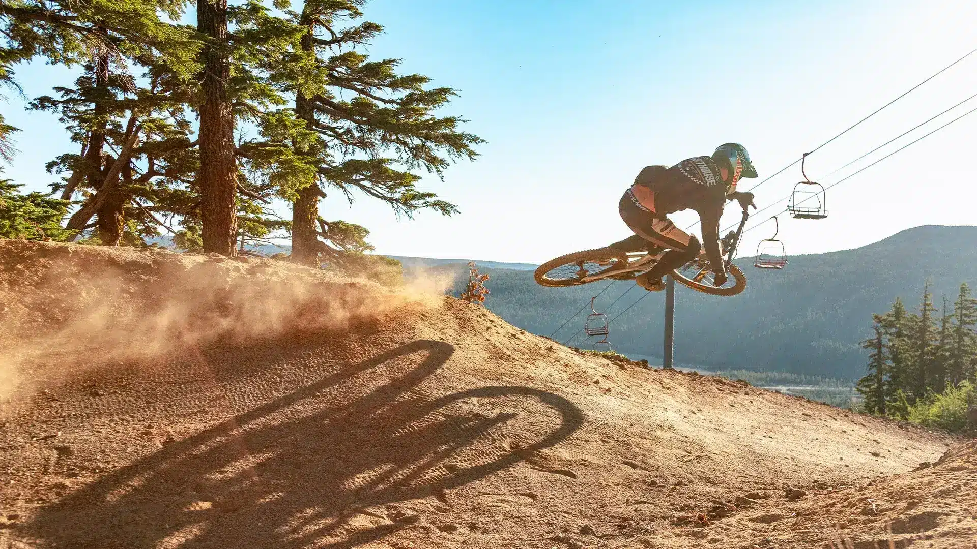 Cyclist jumping downhill riding at Mt. Bachelor with lift in the background