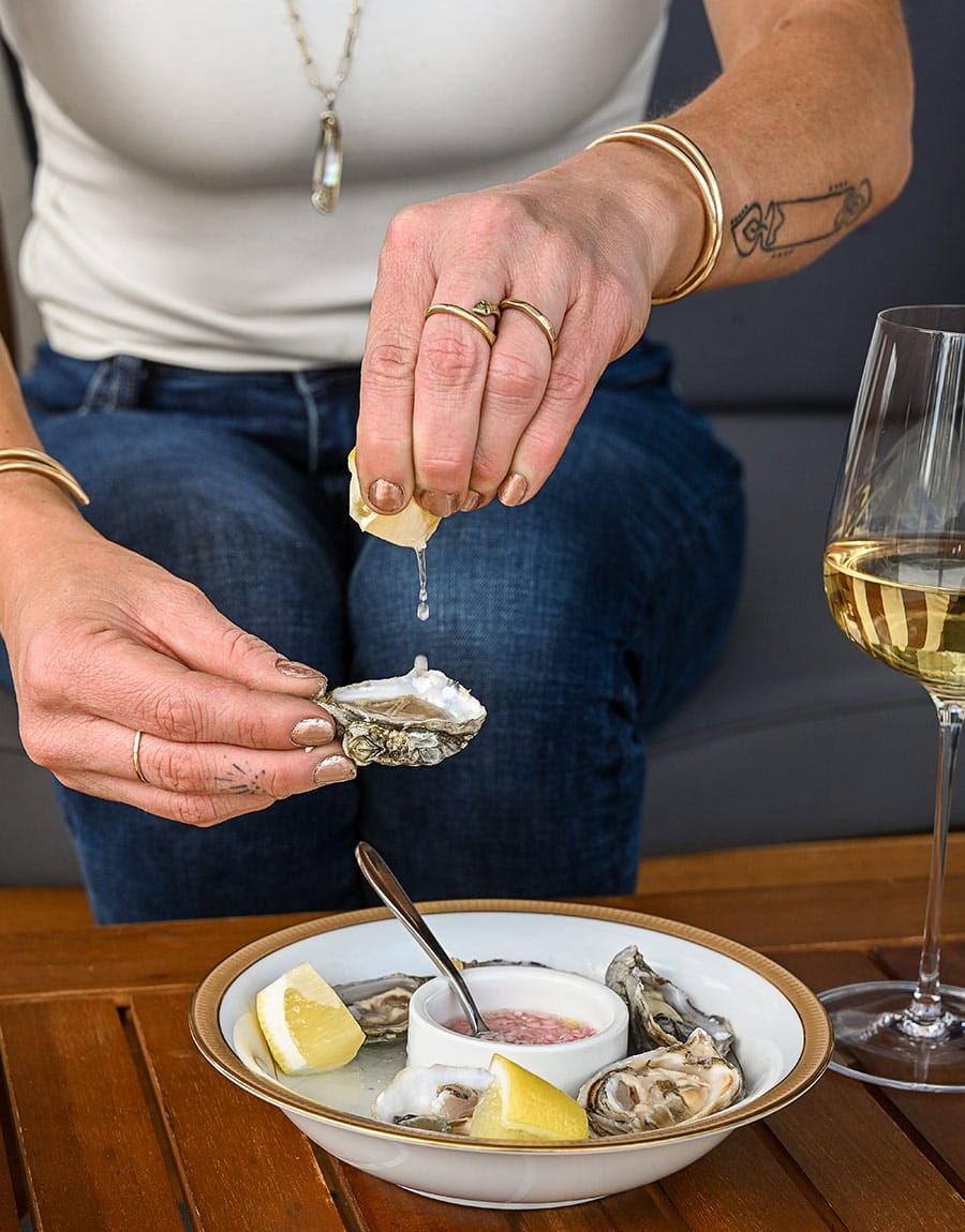 Woman squeezing lemon on Oysters at Viaggio Wine Merchant
