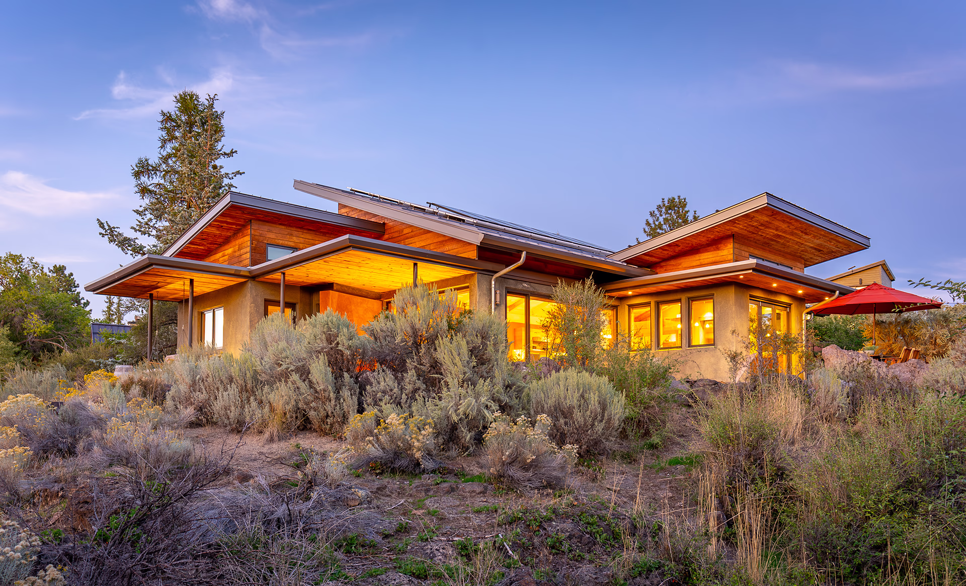 Sustainable Bend home with wood siding, solar panels and native high desert landscaping at dusk