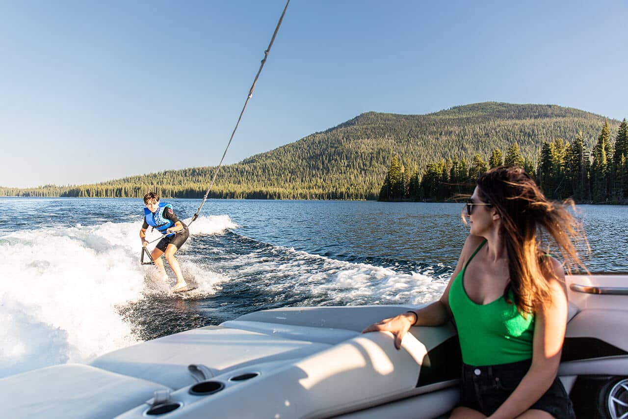 Young boy wakeboarding behind boat while mom watches on Cultus Lake