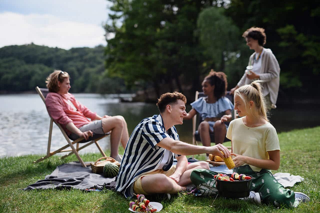 Young adults at the lake grilling and enjoying each other's company.