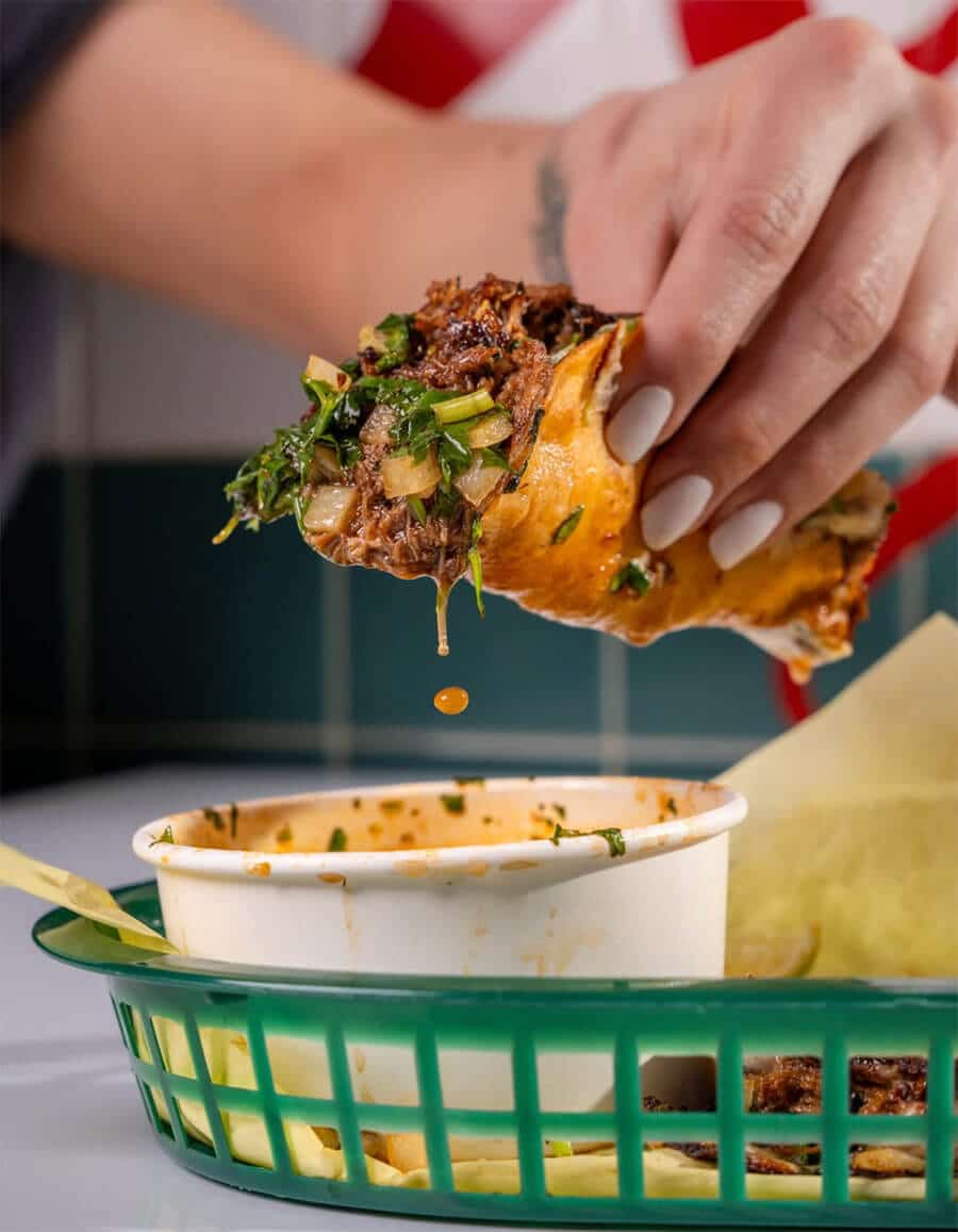 Woman dipping tacos into consume at Papi Chulo's