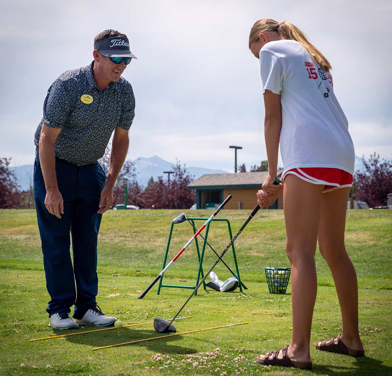 Golfer Nicholas Krohn teaches golf to a student, practicing swing